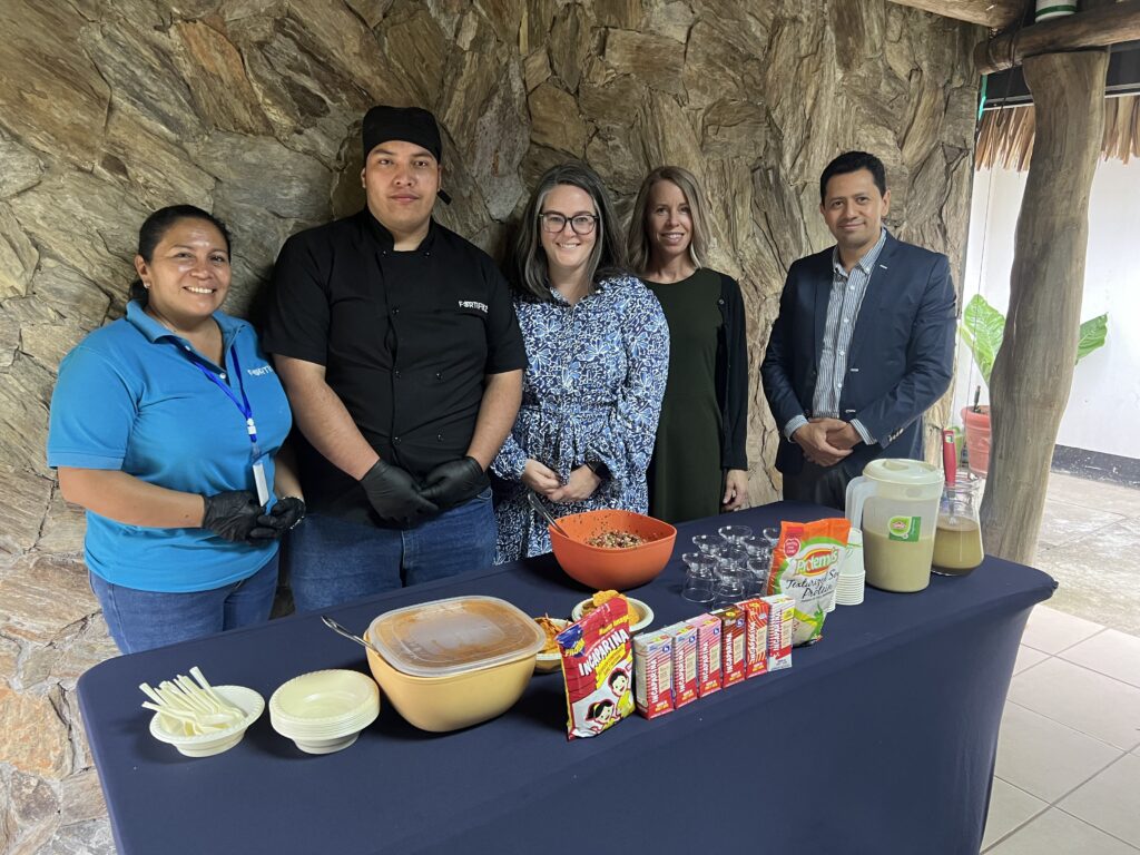 Five people stand behind a table of food products made with soy.