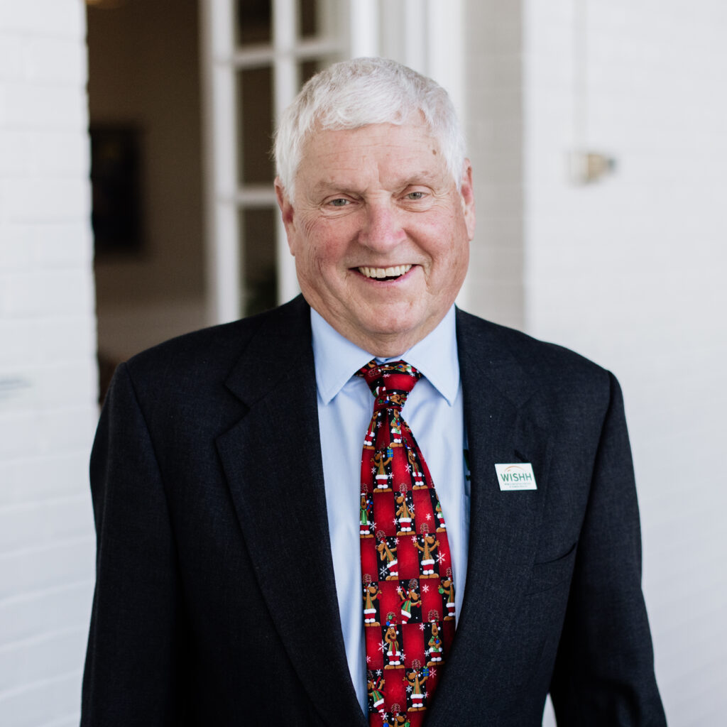 A man in a suit and tie bears the WISHH logo on his lapel.