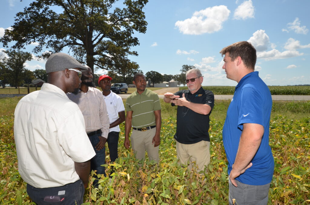 Five people are pictured standing in a soybean field.