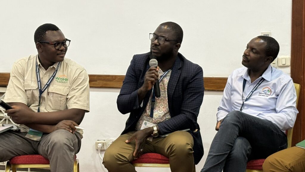 Three men sit with microphones, having a discussion.