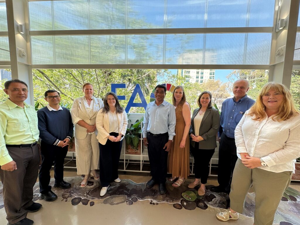 Nine people stand together to pose in front of a window with the FAO logo.